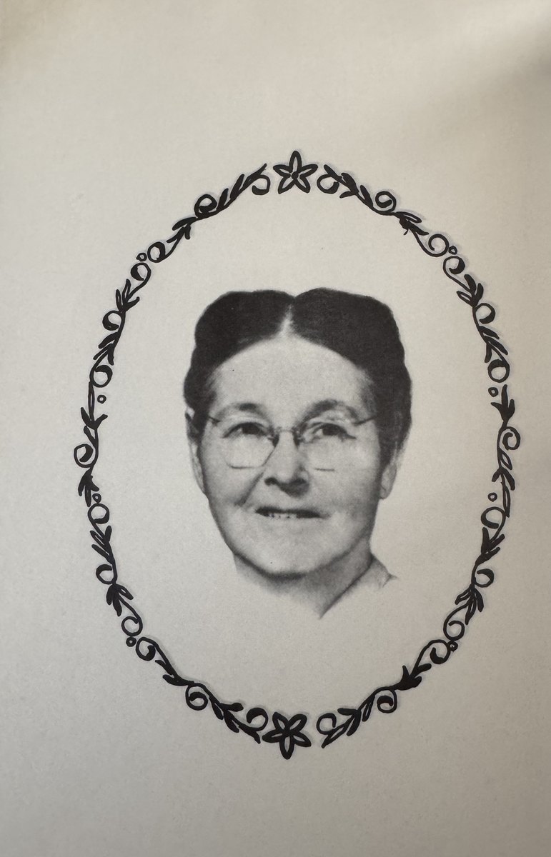 Photograph of an elderly woman in wire-rimmed glasses, inside a hand-drawn oval of leaves and flowers